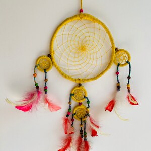 May include: Yellow dream catcher with red and white feathers and colorful beads.