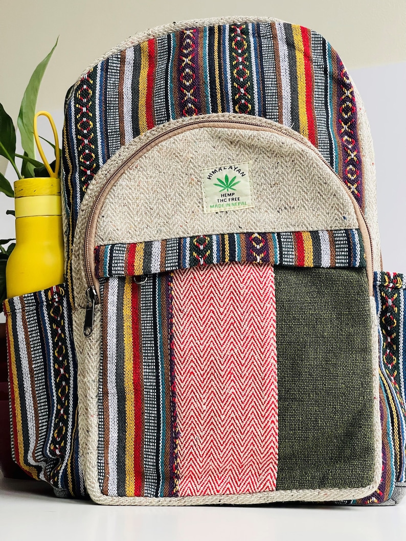 May include: A multi-coloured striped hemp backpack with a large front pocket. The pocket has a brown zipper and a small patch with the text "Himalayan Hemp THC Free Made in Nepal".