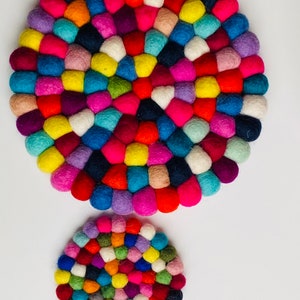 May include: Two round felt coasters in various colors, including red, blue, green, yellow, pink, and purple. The larger coaster is in the background and the smaller coaster is in the foreground.