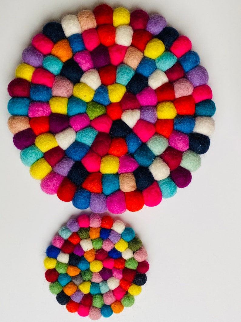 May include: Two round felt coasters in various colors, including red, blue, green, yellow, pink, and purple. The larger coaster is in the background and the smaller coaster is in the foreground.