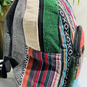 May include: A multi-colored striped and solid fabric backpack with a zippered pocket. The backpack is made of a variety of fabrics, including green, blue, red, and black.