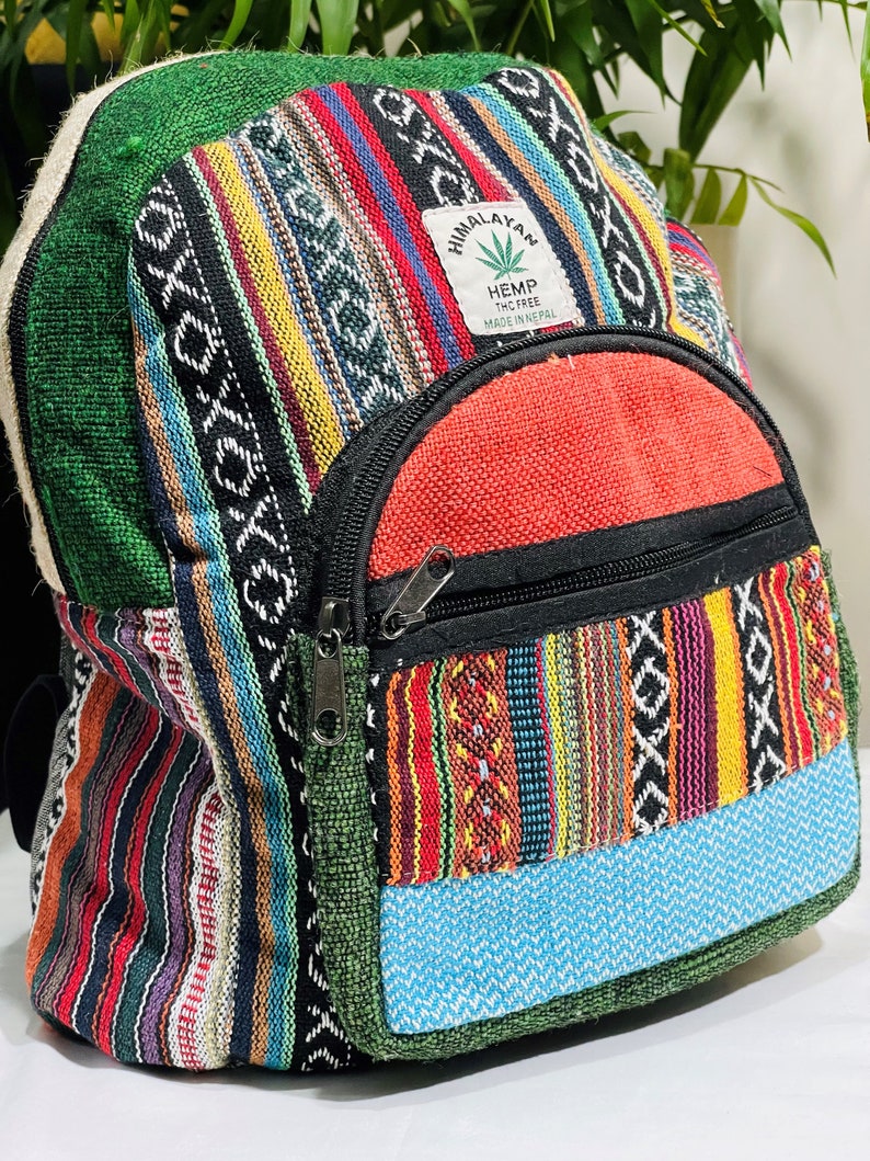 May include: A colorful hemp backpack with a patch that reads "Himalayan Hemp THC Free Made in Nepal". The backpack is made of a patchwork of different fabrics, including green, red, blue, yellow, and black.
