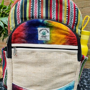 May include: A multi-coloured hemp backpack with a tie-dye design and a patch that says "Himalayan Hemp THC Free Made in Nepal".
