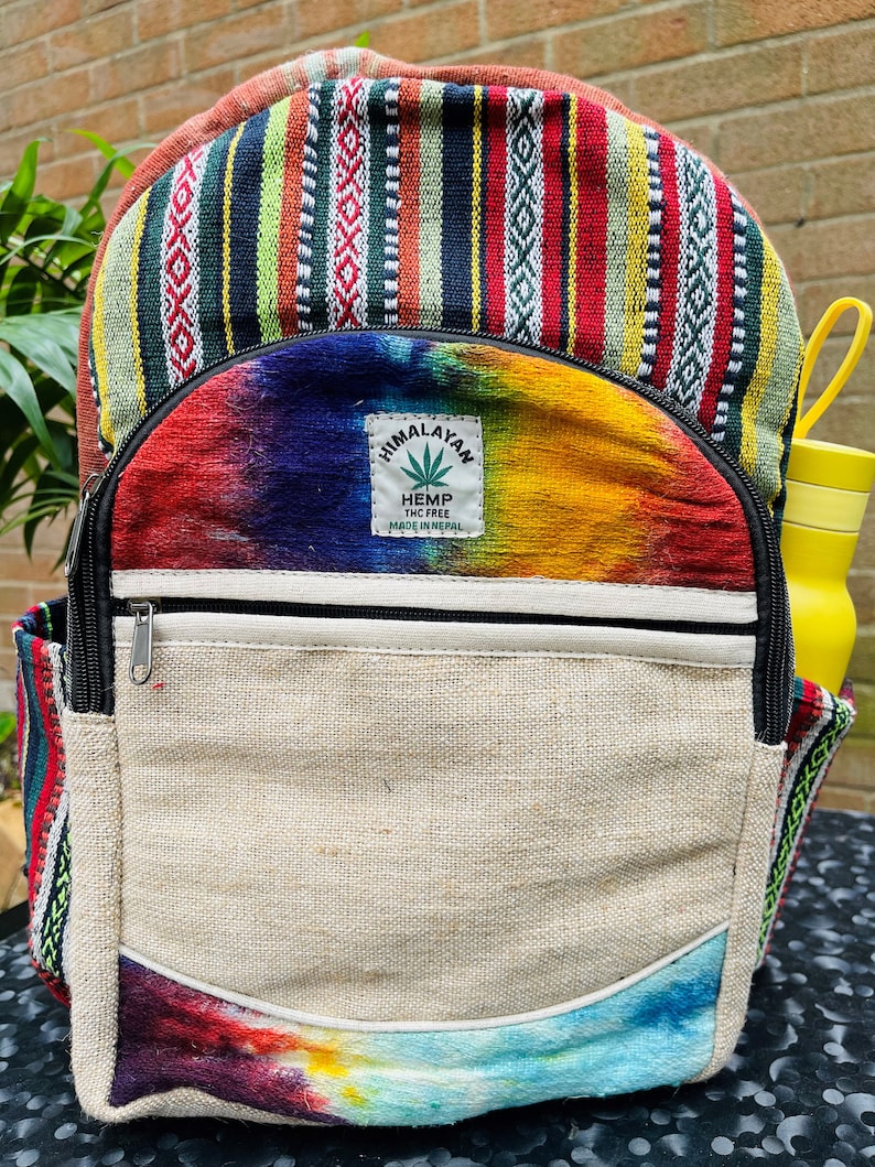 May include: A multi-coloured hemp backpack with a tie-dye design and a patch that says "Himalayan Hemp THC Free Made in Nepal".