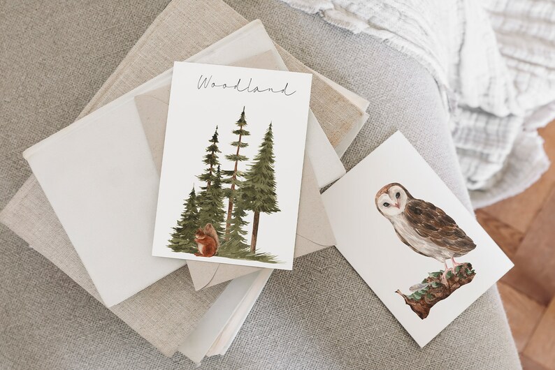 May include: Two watercolor illustrations on white cardstock. The first card features a group of green pine trees with a brown squirrel sitting at the base of the trees. The text "Woodland" is written in black cursive at the top of the card. The second card features a white barn owl with brown markings perched on a branch.