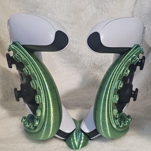 May include: A 3D printed green and white controller stand for two controllers. The stand is shaped like an octopus with tentacles wrapping around the controllers.