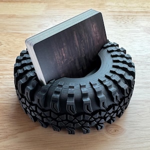 May include: A black 3D printed tire-shaped card holder with a deck of cards inside.