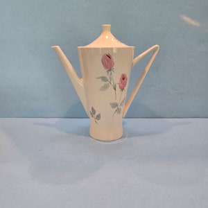 May include: White ceramic coffee pot with a floral design featuring pink roses and green leaves.