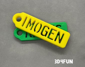 Op de afbeelding: Twee gele en groene plastic sleutelhangers met de naam "IMOGEN" uitgesneden op de gele sleutelhanger.