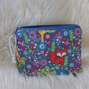 Könnte beinhalten: Eine blaue Reißverschlusstasche mit einem weißen Kordelzug. Die Tasche hat ein buntes Blumenmuster mit einem roten Fuchs in der Mitte.