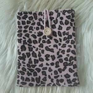 Könnte beinhalten: Eine rechteckige Tasche aus hellrosa geripptem Stoff mit einem dunkelbraunen und schwarzen Leopardenmuster. Die Tasche wird mit einer hellrosa Kordelschlaufe verschlossen, die über einen runden Holzknopf mit der Gravur Handmade with love greift.