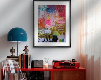 Op de afbeelding: Een moderne woonkameropstelling met een rode kast met een platenspeler, luidsprekers en een blauwe lamp. Een abstract schilderij in een lijst hangt aan de witte muur. Een doorzichtige plastic stoel staat voor de kast.