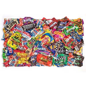 Könnte beinhalten: Eine bunte Auswahl an einzeln verpackten Schokoriegeln und Bonbonsäcken. Die Süßigkeiten umfassen beliebte Marken wie Skittles, Twizzlers, Starburst, Nerds und Snickers.