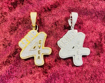 May include: Two pendants, one gold and one silver, both featuring a large number "4" with the word "VEGA" written vertically inside the number. Both pendants are covered in sparkling rhinestones.