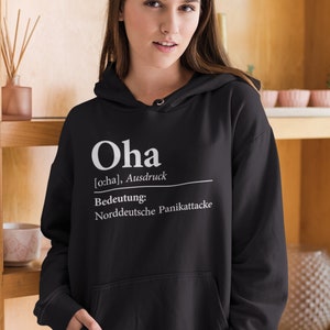 Könnte beinhalten: Schwarzer Kapuzenpullover mit weißem Text, der "Oha [o:ha], Ausdruck Bedeutung: Norddeutsche Panikattacke" lautet.