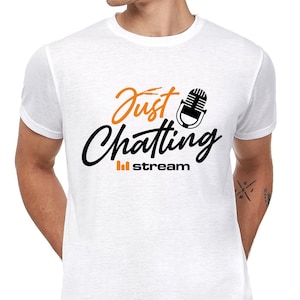 Könnte beinhalten: Weißes T-Shirt mit dem Schriftzug "Just Chatting" in Orange und Schwarz, zusammen mit einer Mikrofon-Grafik. Das Wort "stream" steht unter dem Haupttext in Schwarz. Das T-Shirt hat einen Rundhalsausschnitt.