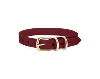 May include: A deep red dog collar featuring a gold-toned metal buckle and two matching gold-toned D-rings. The collar has a series of adjustment holes and the brand name KegDog is embossed on the pointed end of the strap near the hardware.