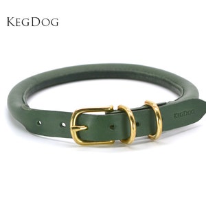 Puede incluir: Un collar de perro de cuero verde oscuro con una hebilla dorada y dos anillos en D. El collar está estampado con el texto "KEGDOG".