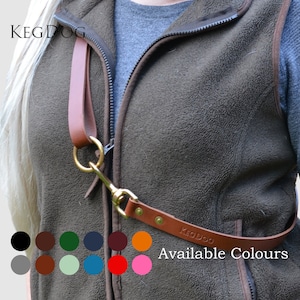 May include: A brown leather hands-free dog leash with brass hardware, featuring a circular ring and a swivel snap hook. The leash is embossed with the text KEGDOG and includes a color chart showing twelve available color options for the product.