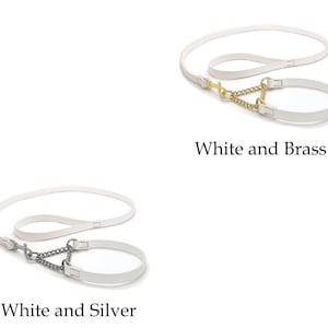 Op de afbeelding: Witte hondenriemen met bijpassende halsbanden. E&eacute;n set heeft een goudkleurige ketting en sluiting, met de tekst "White and Brass" eronder. De andere set heeft een zilverkleurige ketting en sluiting, met de tekst "White and Silver" eronder.