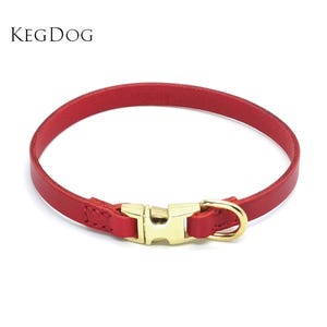 May include: A red leather dog collar with a gold-colored buckle and hardware. The collar is a simple band design with a classic buckle closure. The brand name "KEGDOG" is in the upper left corner.