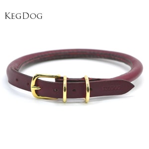 Könnte beinhalten: Ein burgunderfarbenes Lederhundekragen mit einer goldenen Schnalle und zwei goldenen Ringen. Das Halsband ist mit dem Text "KEGDOG" geprägt.