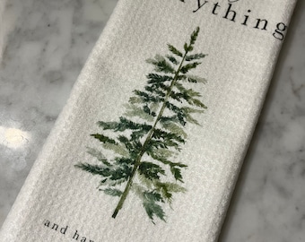 Peut inclure: Essuie-mains blanc avec un motif d'arbre de Noël de style aquarelle. Le torchon porte les mots "merry everything" et "and happy always" imprimés en noir.