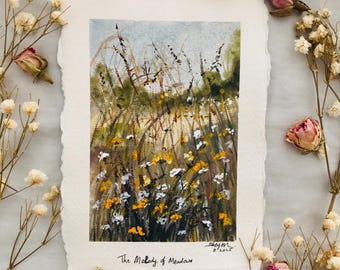 May include: An original watercolor painting of a meadow scene with yellow and white wildflowers, tall grasses, and a light blue sky. The painting is on textured paper and is titled "The Melody of Meadow".
