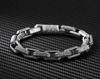 May include: A silver chain bracelet with an intricate floral pattern on each link. The bracelet has a magnetic clasp.