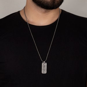 Puede incluir: Un collar de cadena de plata con un colgante de plata con un dise&ntilde;o geom&eacute;trico. El colgante es de forma rectangular y tiene un patr&oacute;n detallado.