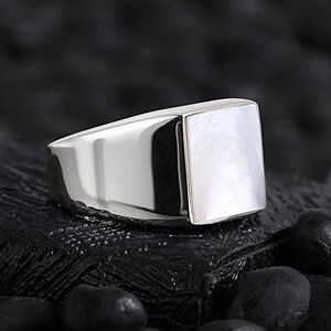 May include: A silver ring with a square white mother-of-pearl inlay.