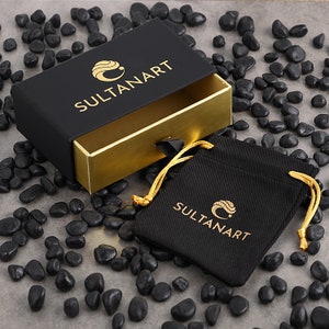 May include: A black box with a gold interior and a black drawstring bag. The box and bag both have the logo "SULTANART" printed on them.