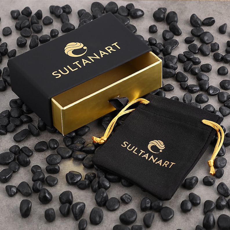May include: A black box with a gold interior and a black drawstring bag. The box and bag both have the logo "SULTANART" printed on them.