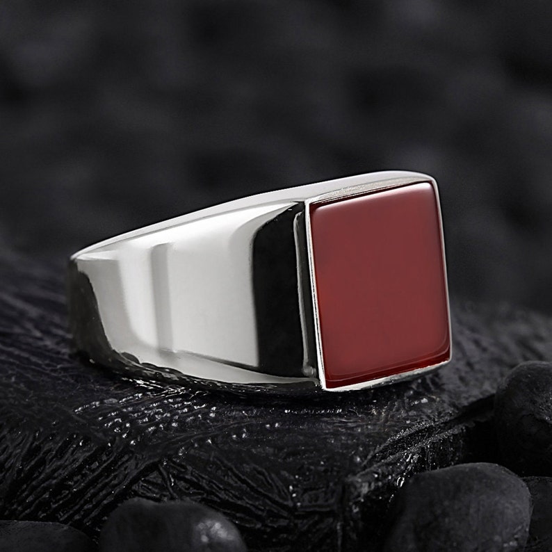 May include: A silver ring with a square red gemstone.