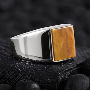 May include: A silver ring featuring a square tiger's eye gemstone.