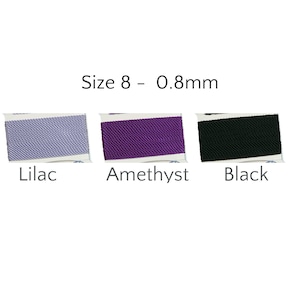 May include: Three spools of Size 8 - 0.8mm cord in Lilac, Amethyst, and Black. The colors are displayed on white labels. The text "Size 8 - 0.8mm" is above the spools. The word "Lilac" is under the first spool, "Amethyst" under the second, and "Black" under the third.