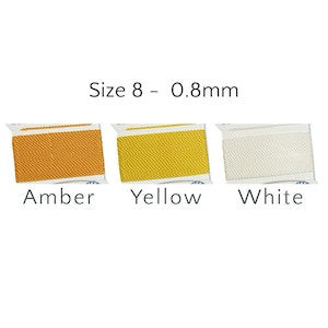 May include: Three spools of Size 8 - 0.8mm cord in amber, yellow, and white. The spools are neatly arranged, showcasing the different colors of the cord. The text "Amber", "Yellow", and "White" is printed below each spool.