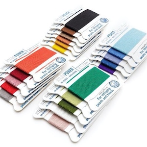 May include: A selection of nylon thread spools in a range of colours, such as black, brown, yellow, red, pink, green, blue, and purple. Each spool is labelled with the text "NYLON POWER" and "For stringing pearls and beads."