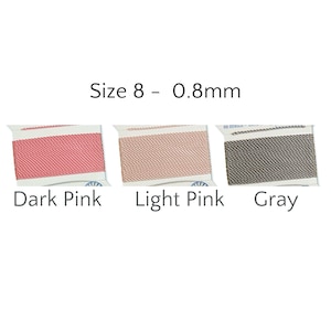 May include: Three spools of Size 8 - 0.8mm thread in dark pink, light pink, and gray. The spools are labeled with their respective colors. The thread is tightly wound on white spools.