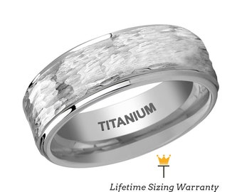 May include: A silver titanium ring with a textured, hammered finish. The word "TITANIUM" is engraved on the inside of the ring. The ring has a rounded shape and a polished edge. The image also includes the text "Lifetime Sizing Warranty".