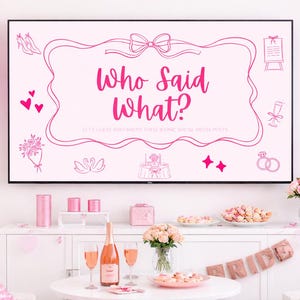 Peut inclure: Mise en scène pour une fête de mariage rose, avec un écran de télévision affichant le texte "Who Said What?". La décoration comprend des ballons roses, des fleurs, du champagne et des desserts. L'ambiance est festive.