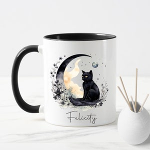 May include: White ceramic mug with a black handle and a black rim. The mug features a black cat sitting on a crescent moon with a watercolour-style design. The text "Felicity" is printed on the bottom of the mug.