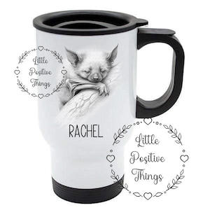 May include: White travel mug with a black handle and lid. The mug features a black and white illustration of a bat sleeping on a branch. The text "Little Positive Things" is written in a circle around the bat. The name "RACHEL" is written below the bat.