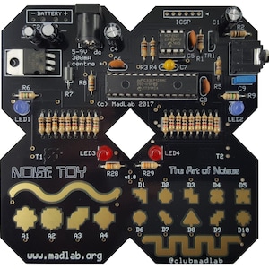 Puede incluir: Una placa de circuito negro con componentes electrónicos, incluyendo resistencias, LEDs y circuitos integrados. La placa presenta el texto "NOISE TOY" y el texto "The Art of Noises" y "www.madlab.org".