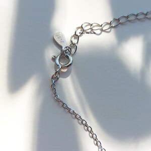 May include: Silver chain necklace with a lobster clasp closure. The tag on the chain reads "Merci Ma Belle".