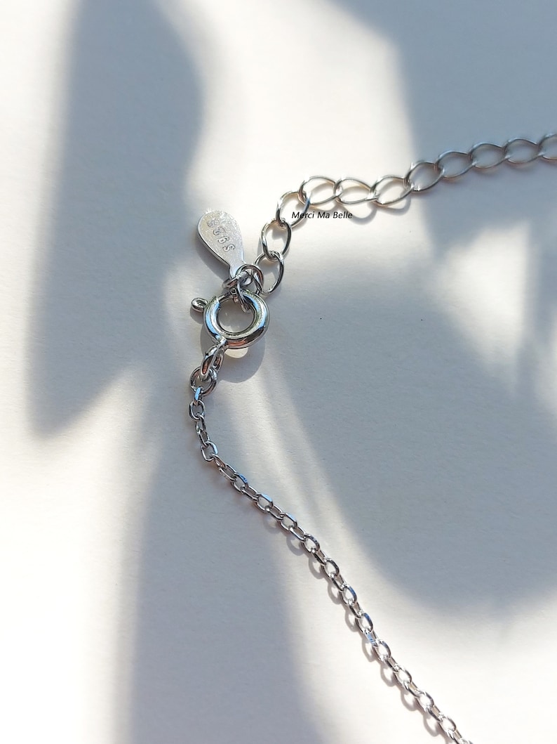 May include: Silver chain necklace with a lobster clasp closure. The tag on the chain reads "Merci Ma Belle".