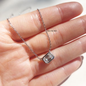 May include: A silver chain necklace with a clear rectangular pendant. The pendant is set in a silver bezel.