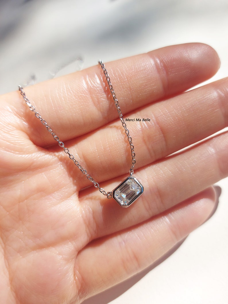 May include: A silver chain necklace with a clear rectangular pendant. The pendant is set in a silver bezel.