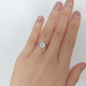 May include: A silver engagement ring with a large, round, clear diamond.