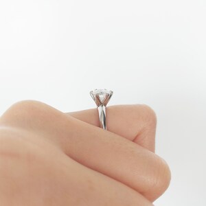 May include: A silver engagement ring with a round, clear diamond.